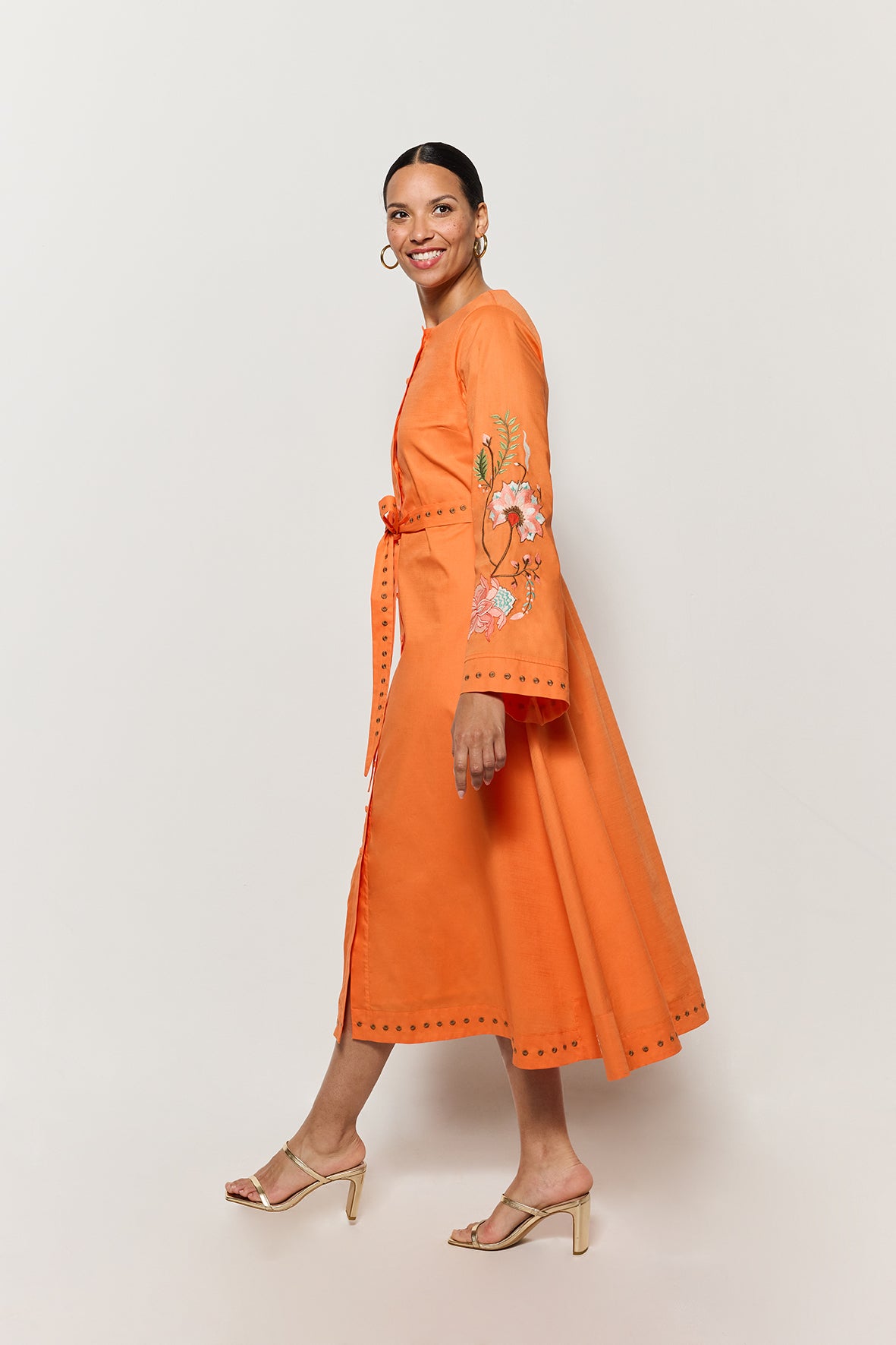 Model in Fanm Mon Lagos Dress showcasing bell sleeve  and floral embroidery details , side view. 