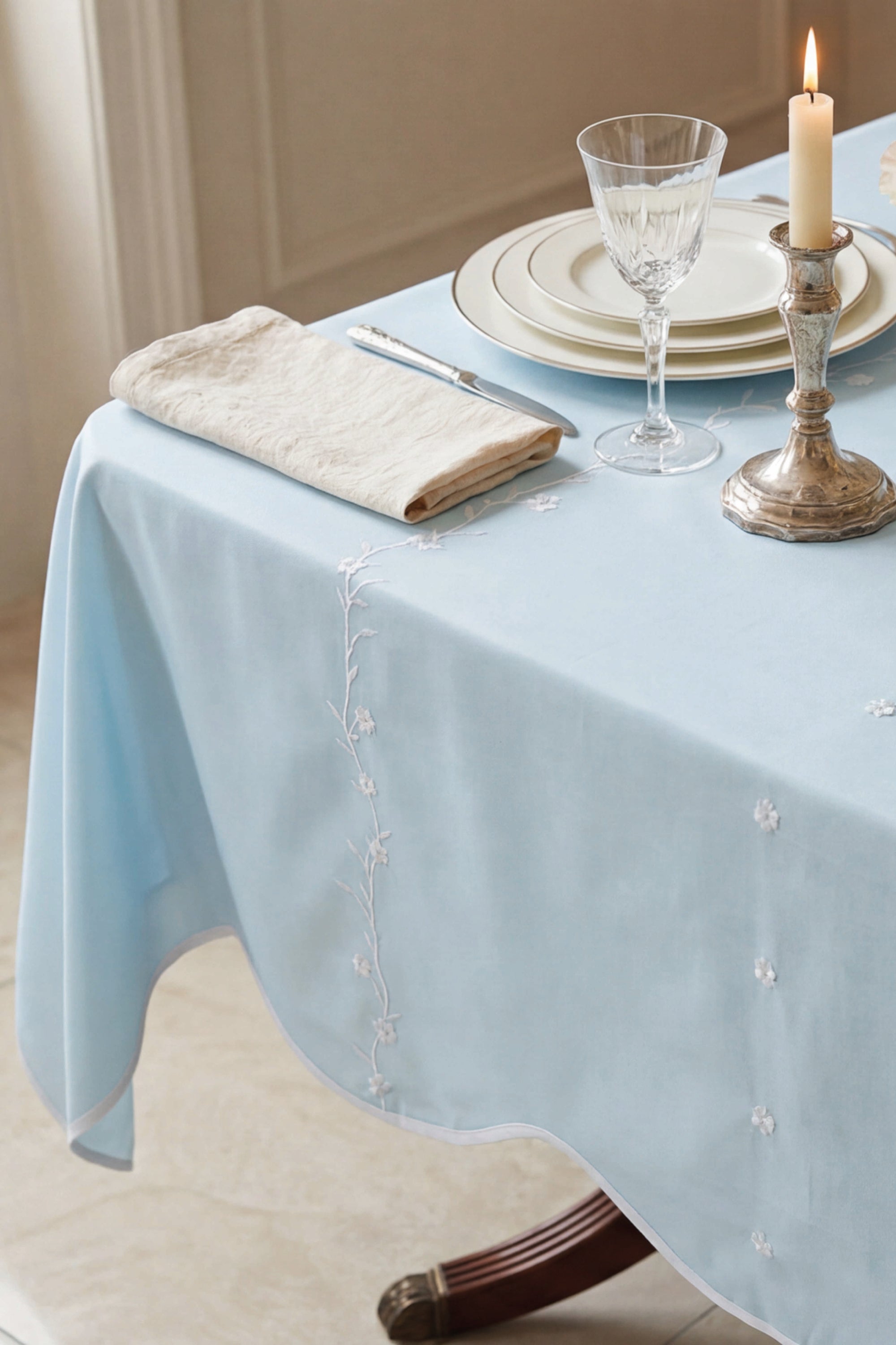 Light lagoon  tablecloth with decorative edge on a set dining table.