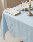 Light lagoon  tablecloth with decorative edge on a set dining table.