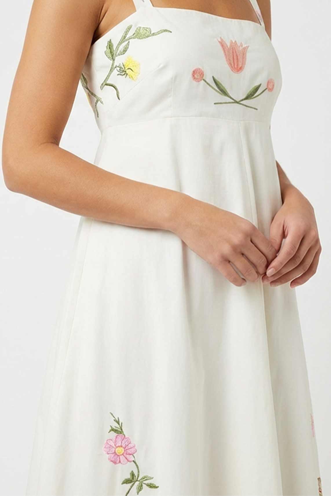 Close-up of the Fanm Mon Leyla Dress highlighting embroidered tulip and buttercup motifs across the bodice with a square neckline and empire waist seam.