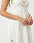Close-up of the Fanm Mon Leyla Dress highlighting embroidered tulip and buttercup motifs across the bodice with a square neckline and empire waist seam.