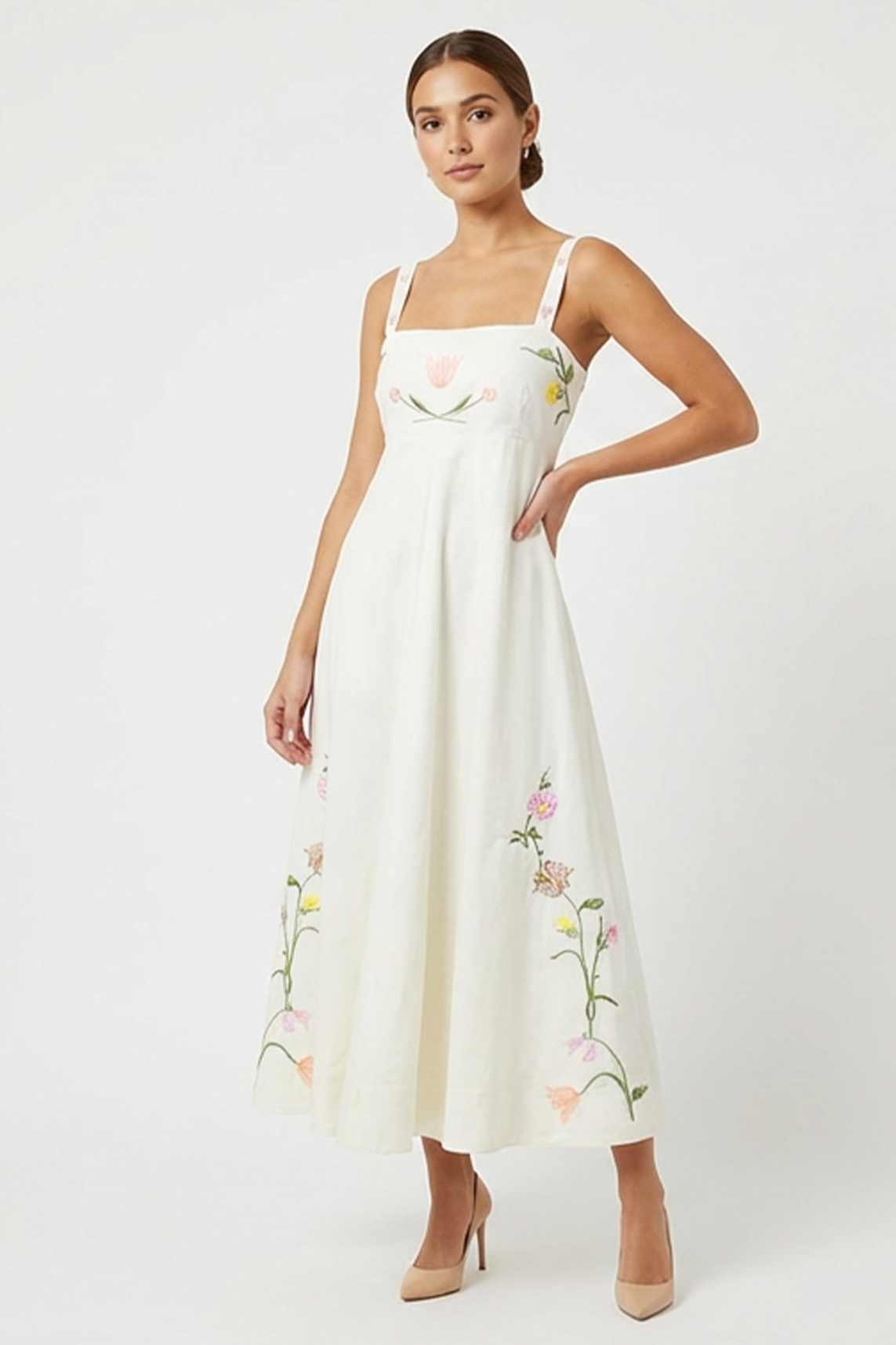 Model wearing the Fanm Mon Leyla Dress featuring tulip, cosmos, buttercup, and lily embroidery, a square neckline, embroidered straps, empire waist, and flowing A-line silhouette.
