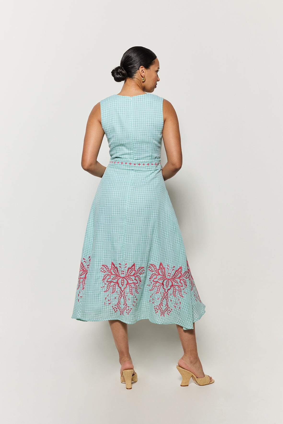 Backview of model wearing Fanm Mon's Libya Midi Dress in Green Check plaid with pink floral embroidery on a white background