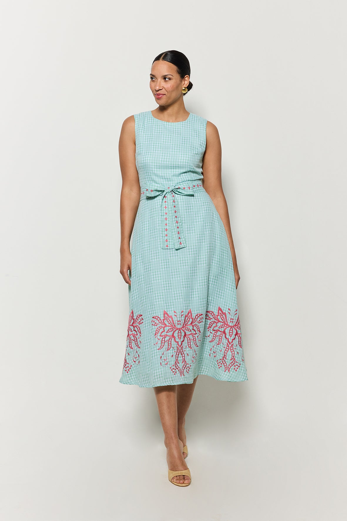 Model wearing Fanm Mon's Libya Midi Dress in Green Check plaid with pink floral embroidery on a white background