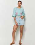 Woman wearing Fanm Mon's Motanka  embroidered slightly cropped top in  green checker plaid and denim shorts on a white background