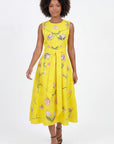 Model wearing the Fanm Mon Nosa Dress featuring tulip-inspired floral embroidery, sleeveless silhouette, self-tie waist belt, and flowing midi skirt in back view against a neutral background.