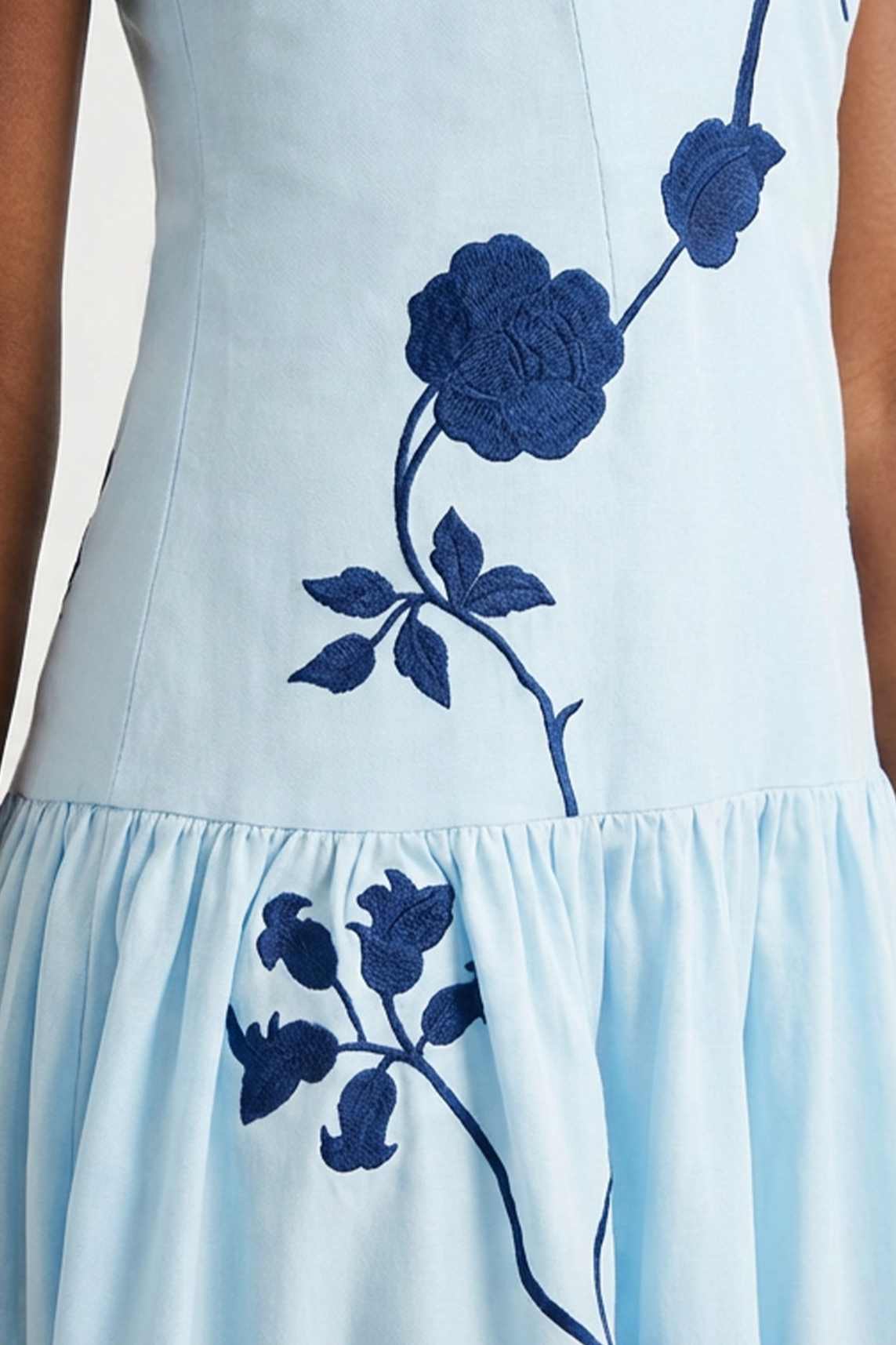 Close-up of the Paola Dress showcasing oversized blue floral embroidery and gathered skirt detailing.