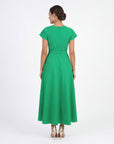 Model wearing the Fanm Mon Ritaj Dress with botanical wildflower embroidery, cap sleeves, adjustable waist tie, and elegant full-length skirt in back view against a neutral studio background.