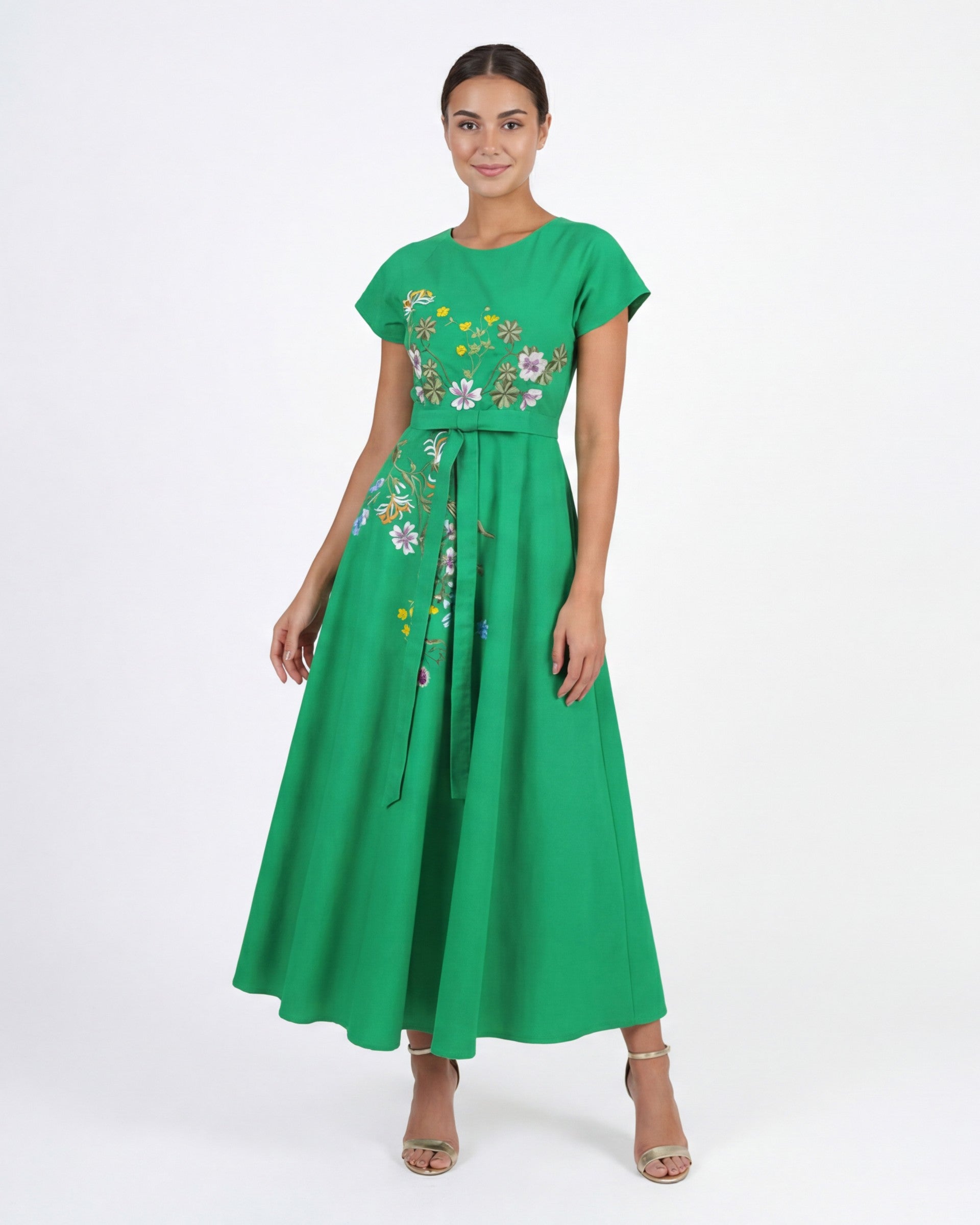 Model wearing the Fanm Mon Ritaj Dress featuring wildflower-inspired embroidery, cap sleeves, adjustable waist tie, and flowing full-length silhouette against a neutral studio background.