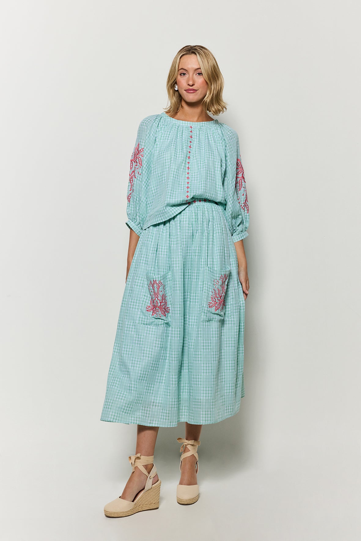 Model wearing Fanm Mon 2 Piece Skirt set in green checker plaid with pink embroidery against a white background