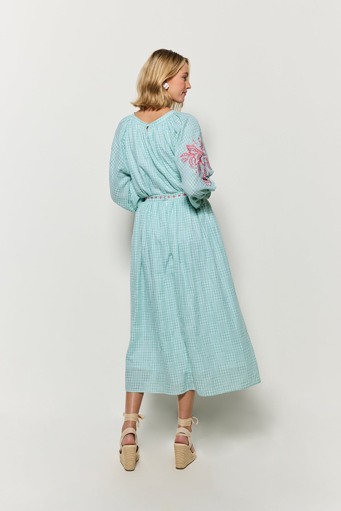 Backview of Model wearing Fanm Mon 2 Piece Skirt set in green checker plaid with pink embroidery against a white background