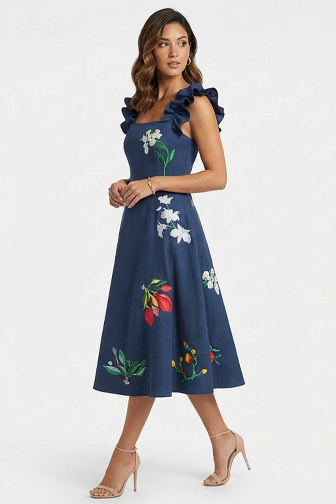 Woman wearing embroidered Tasya midi dress with ruffled shoulder straps and scattered jasmine, orchid, and tropical floral embroidery.
