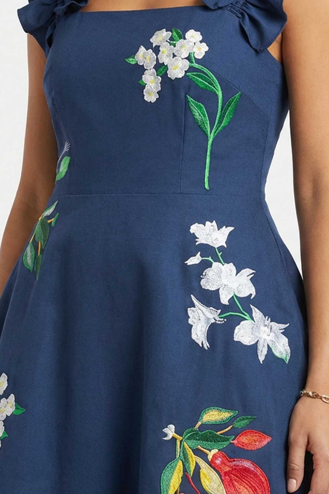 Close-up of hand-placed jasmine blossom, orchid, and tropical floral embroidery on the bodice.