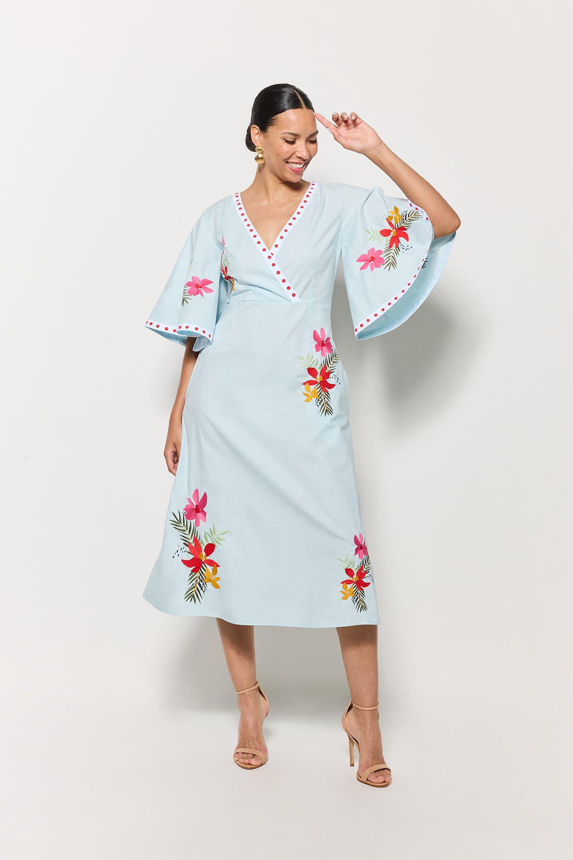 Model in Fanm Mon Tinto Dress in light lagoon with floral embroidery on a white background showcasing movement and front v-neck details