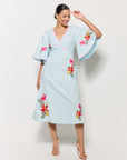 Model in Fanm Mon Tinto Dress in light lagoon with floral embroidery on a white background showcasing movement and front v-neck details