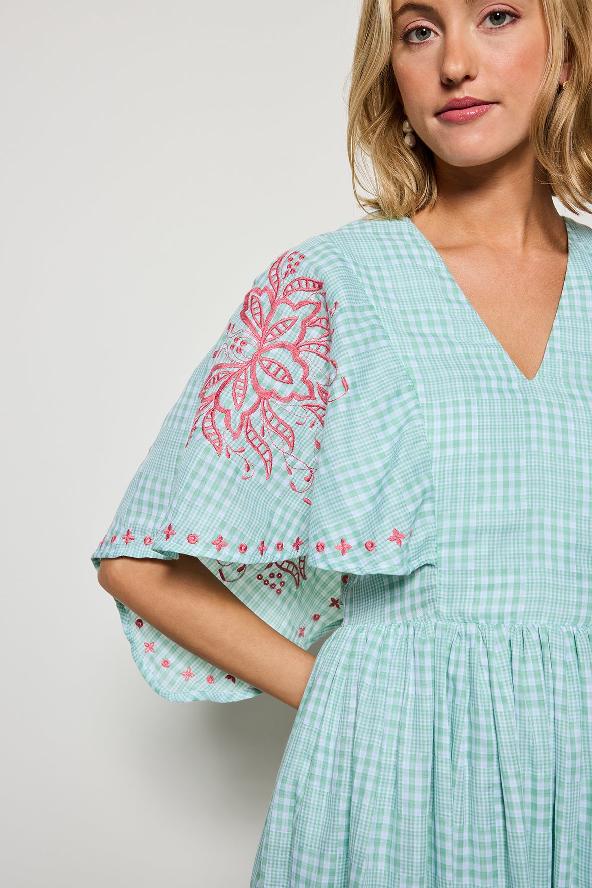 Detail shot of  Fanm Mon's Tunus Midi Dress in Green Check plaid with pink floral embroidery showcasing sleeve detail.  