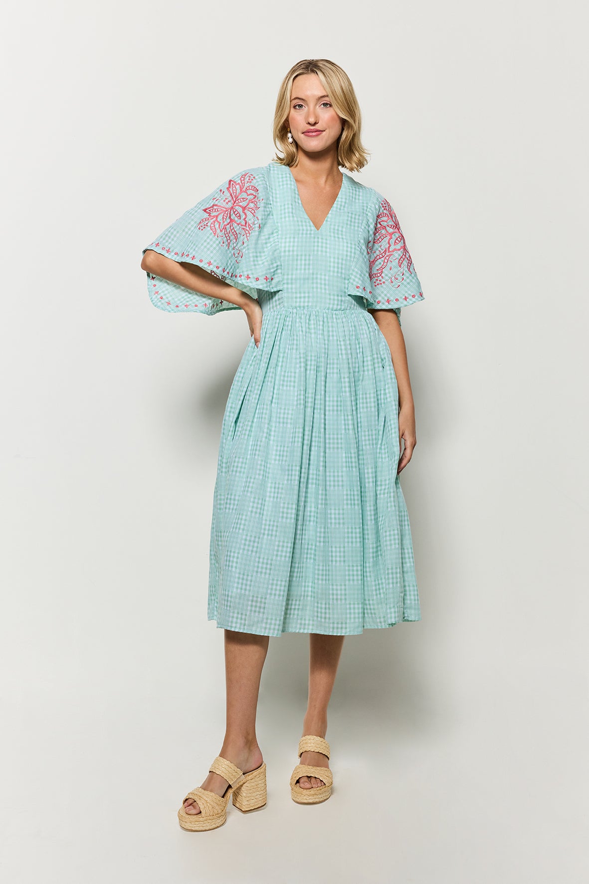 Model wearing Fanm Mon's Tunus Midi Dress in Green Check plaid with pink floral embroidery on a white background