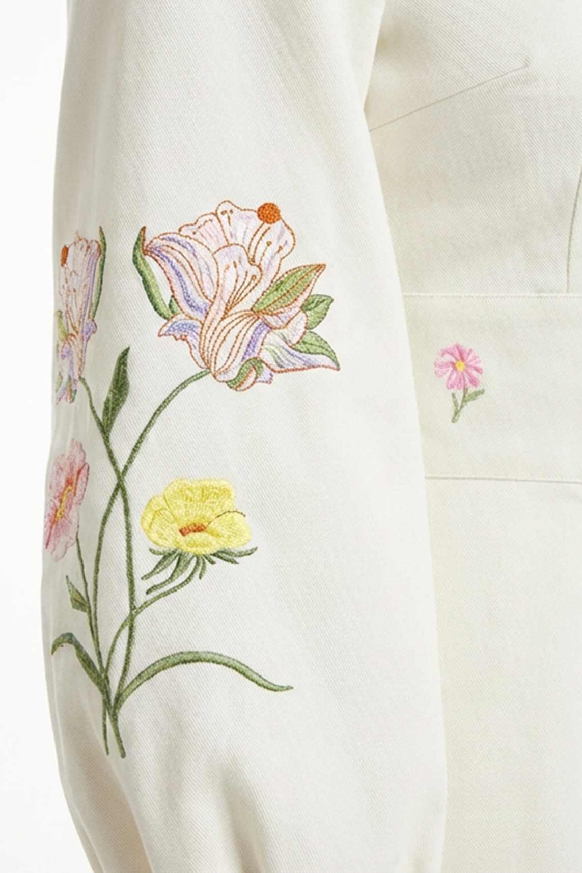 Close-up of the Verona Dress highlighting intricate lily, buttercup, and wildflower embroidery with delicate botanical detailing.