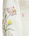 Close-up of the Verona Dress highlighting intricate lily, buttercup, and wildflower embroidery with delicate botanical detailing.