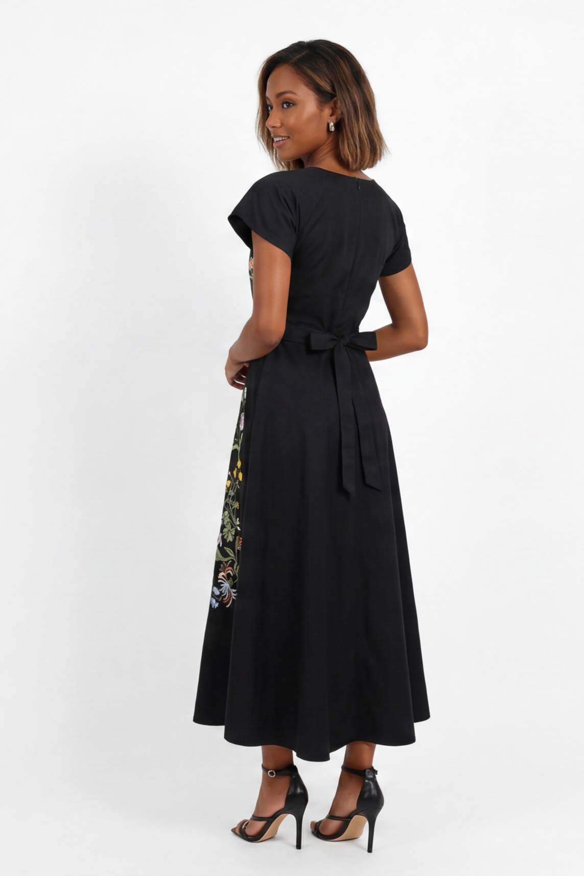 Back view of embroidered midi dress featuring softly structured silhouette and botanical floral embroidery along the skirt panels.