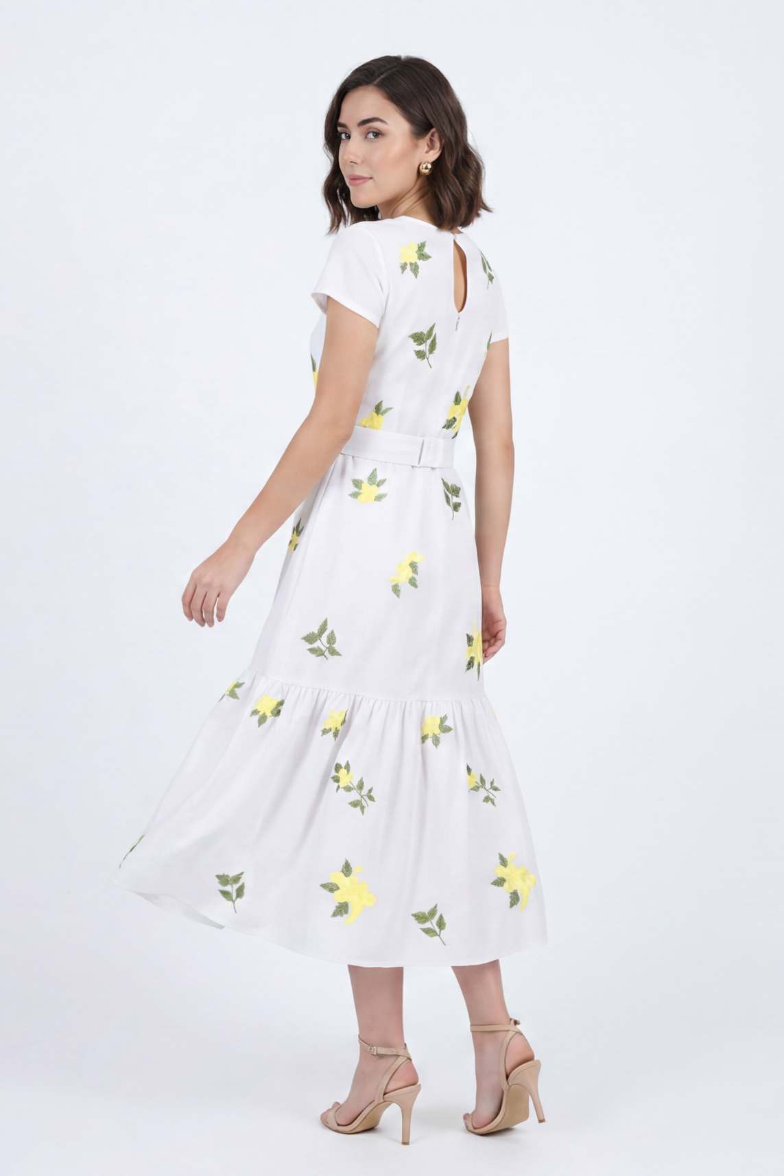 Back view of the Katrina Dress in white with yellow embroidered flowers, gathered skirt detailing, removable waist belt, and keyhole back closure.