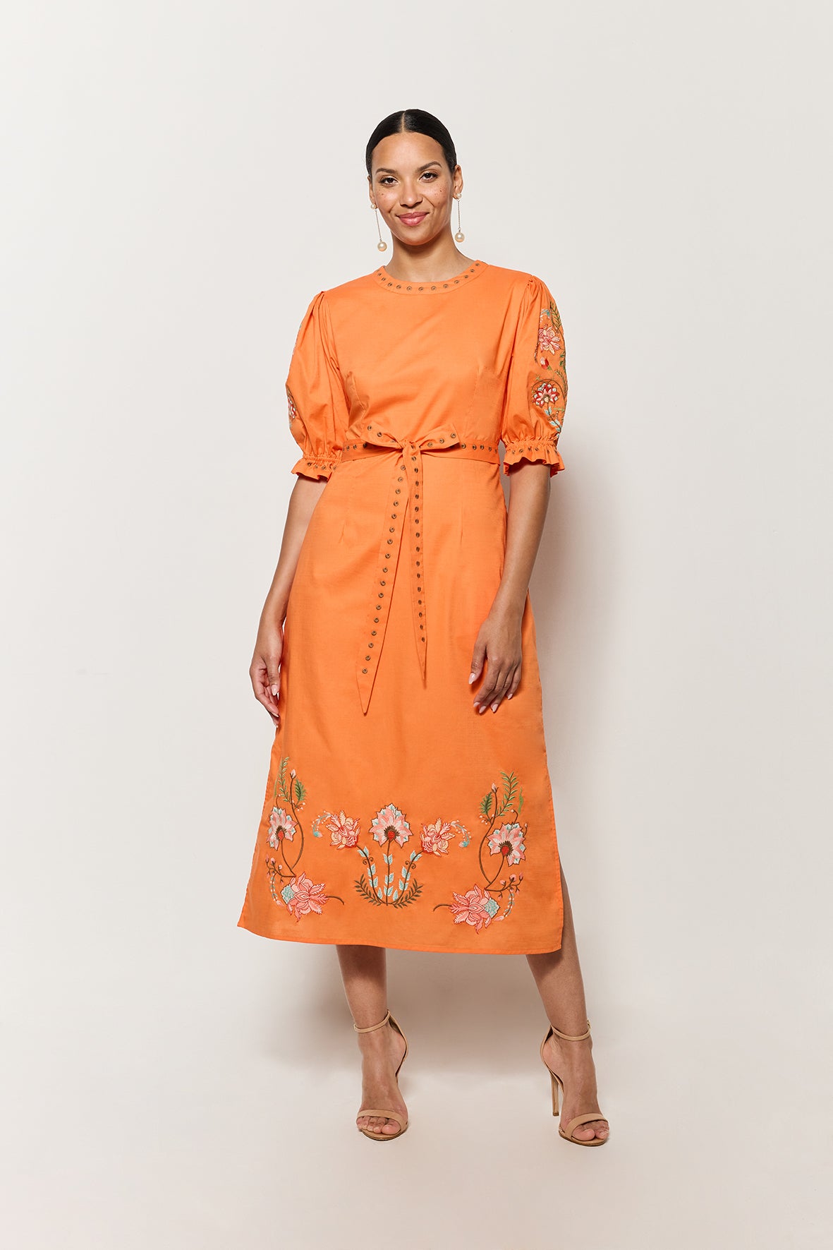 Model Wearing Fanm Mon Pintada Midi Length Dress in Orange with floral embroidery details on white background
