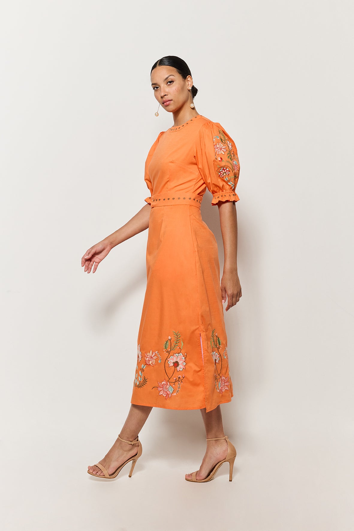 Sideview Model Wearing Fanm Mon Pintada Midi Length Dress in Orange, Showcasing the sleeve detail and shape. 