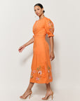 Sideview Model Wearing Fanm Mon Pintada Midi Length Dress in Orange, Showcasing the sleeve detail and shape. 