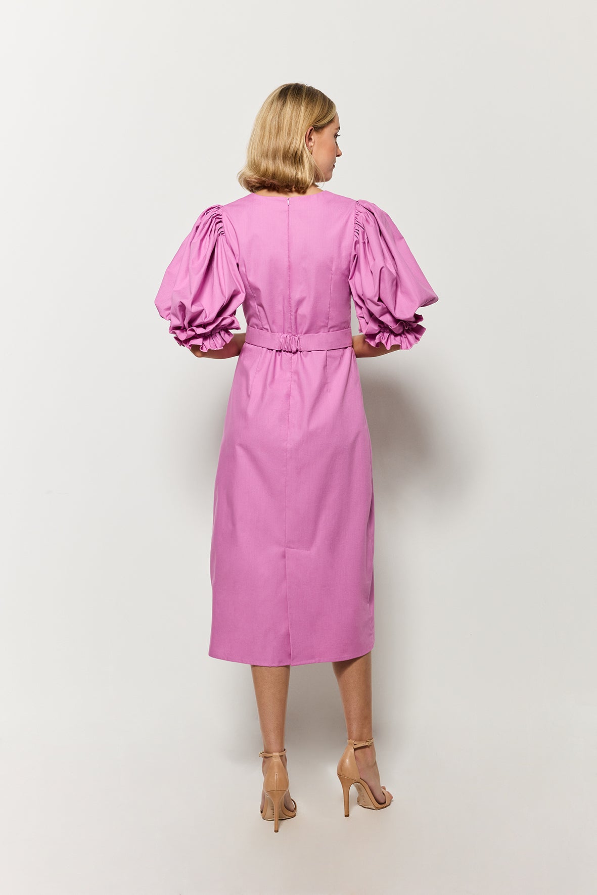 Model wearing a  Fanm Mon deep plum dress with puffed sleeves, showcasing back zipper closure and back slit. 