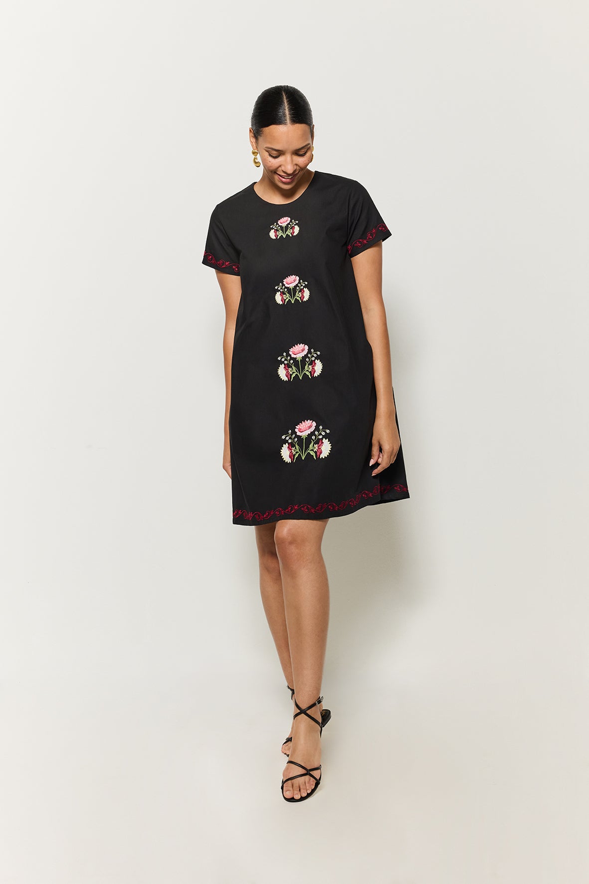 Woman wearing a black dress with floral embroidery on a white background