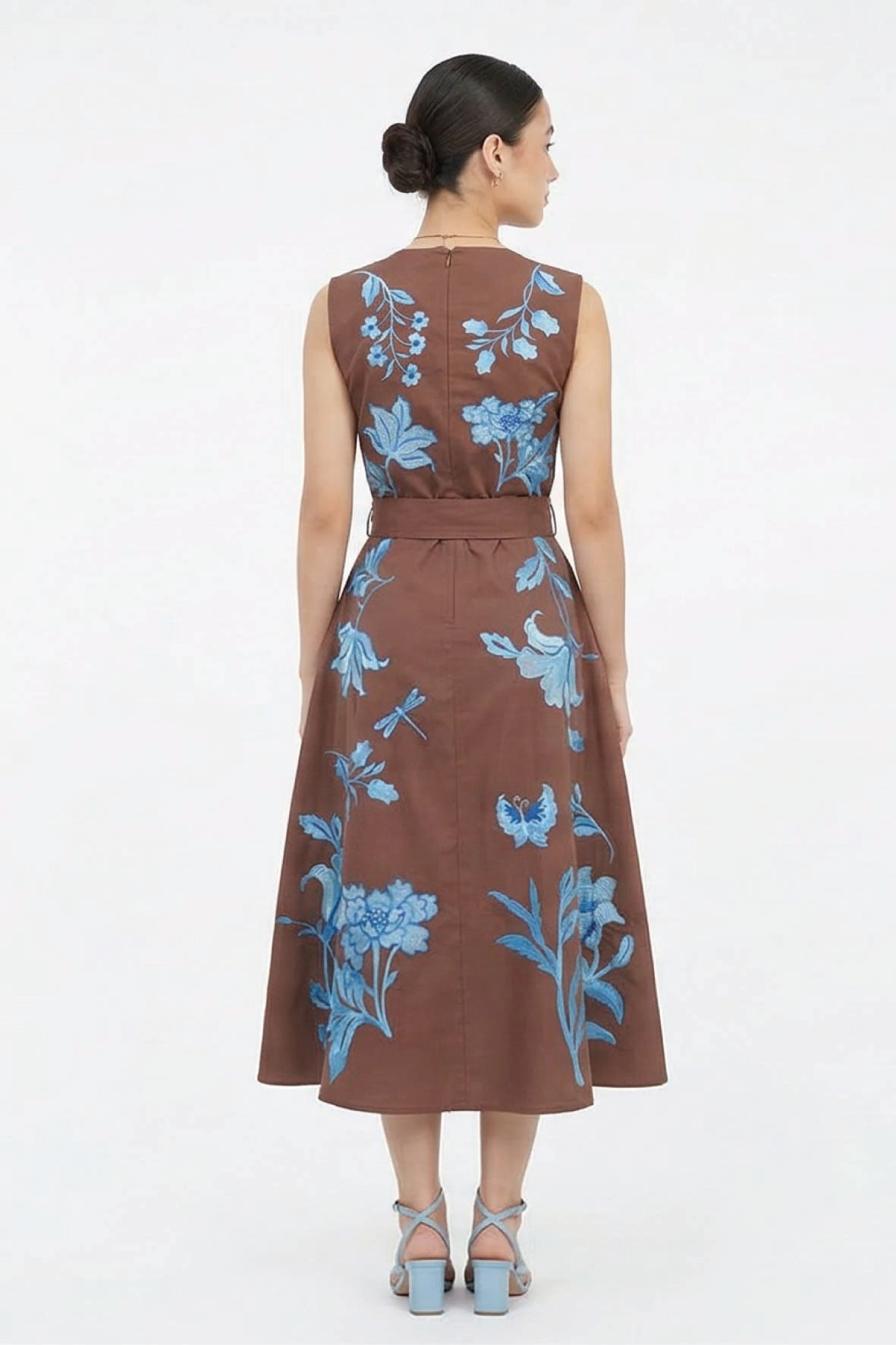 Back view of the Fanm Mon Gera Dress featuring blue botanical and floral embroidery, delicate insect motifs, a defined waist, and full midi skirt.