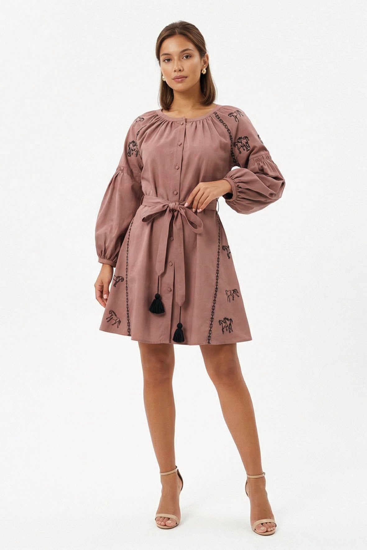 Model wearing the Fanm Mon Hayal Dress featuring a button-front closure, horse embroidery, voluminous sleeves, tassel accents, and a self-tie waist belt. Perfect for Horse lovers.