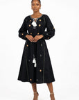 Model wearing the Fanm Mon Lavina Dress featuring floral embroidery, voluminous sleeves, a self-tie waist belt, and tassel neckline.