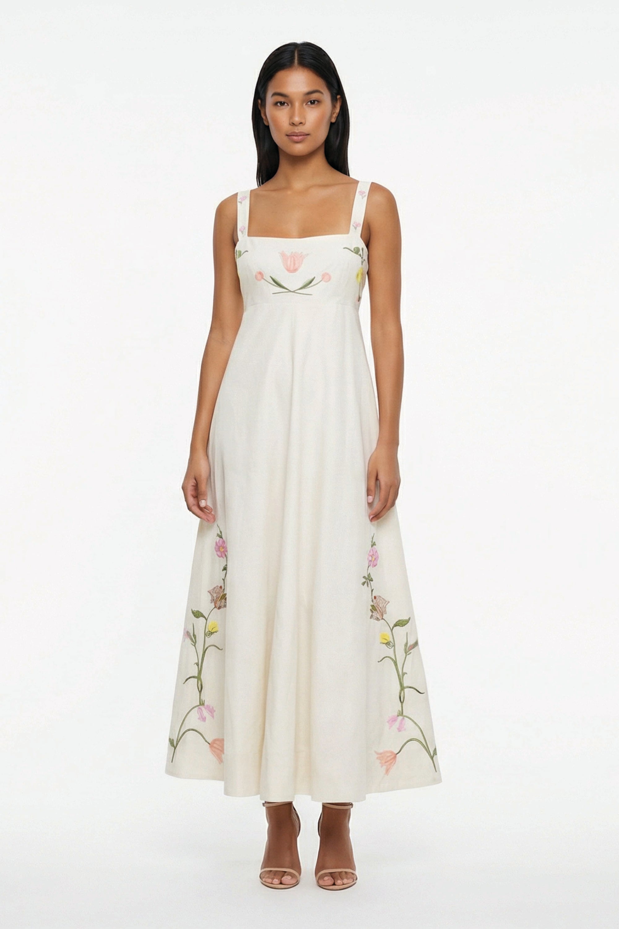 Striaght on view of Model wearing the Fanm Mon Leyla Dress featuring tulip, cosmos, buttercup, and lily embroidery, a square neckline,  and embroidered straps.
