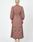 Back view of the Fanm Mon Sakura Dress featuring black horse embroidery, blouson sleeves, a braided waist belt, and double embroidered trim along the midi hem.