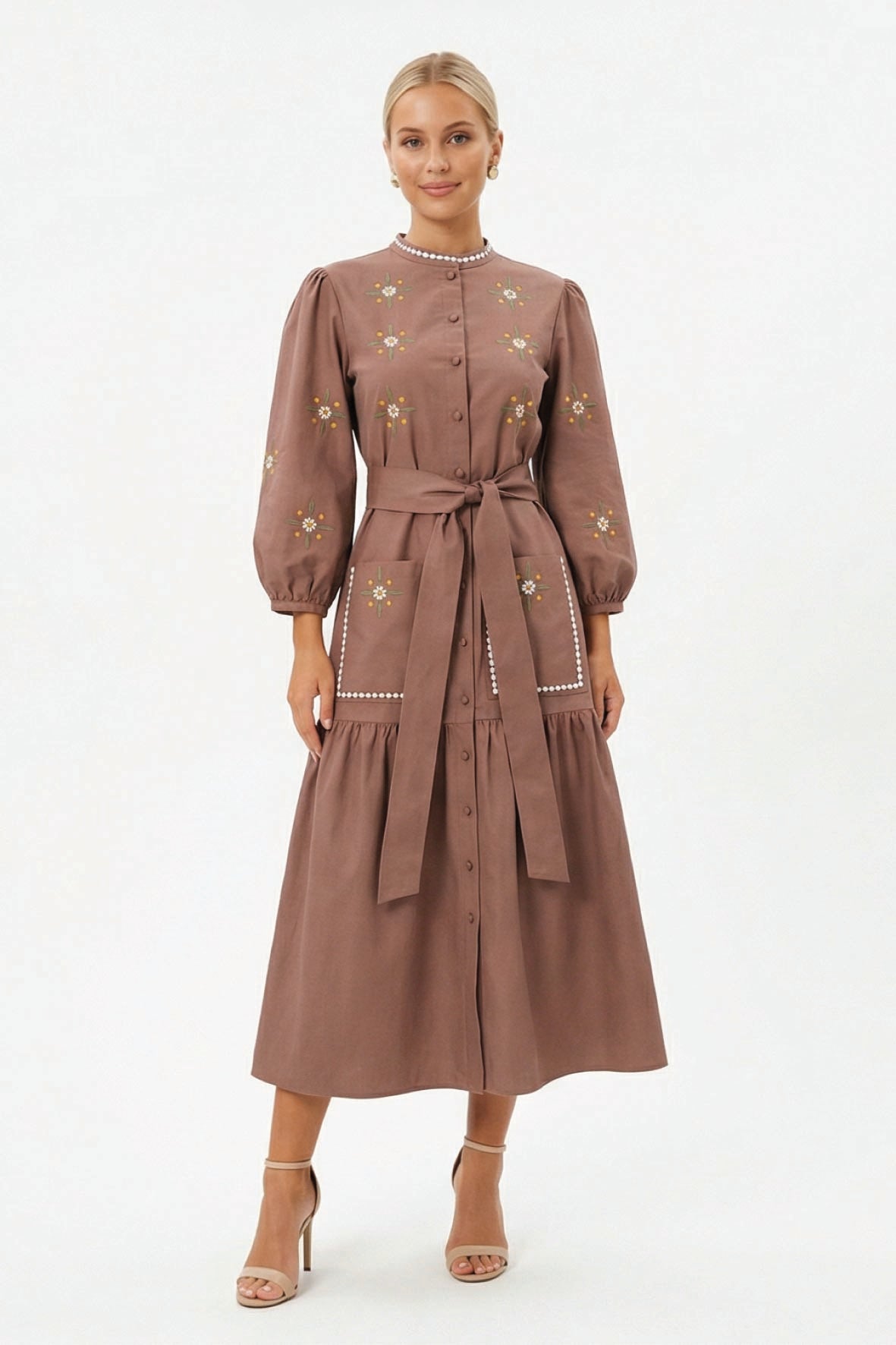 Model wearing the Fanm Mon Samara Dress featuring floral embroidery, three-quarter blouson sleeves, oversized patch pockets, a self-tie waist belt, and gathered midi skirt.
