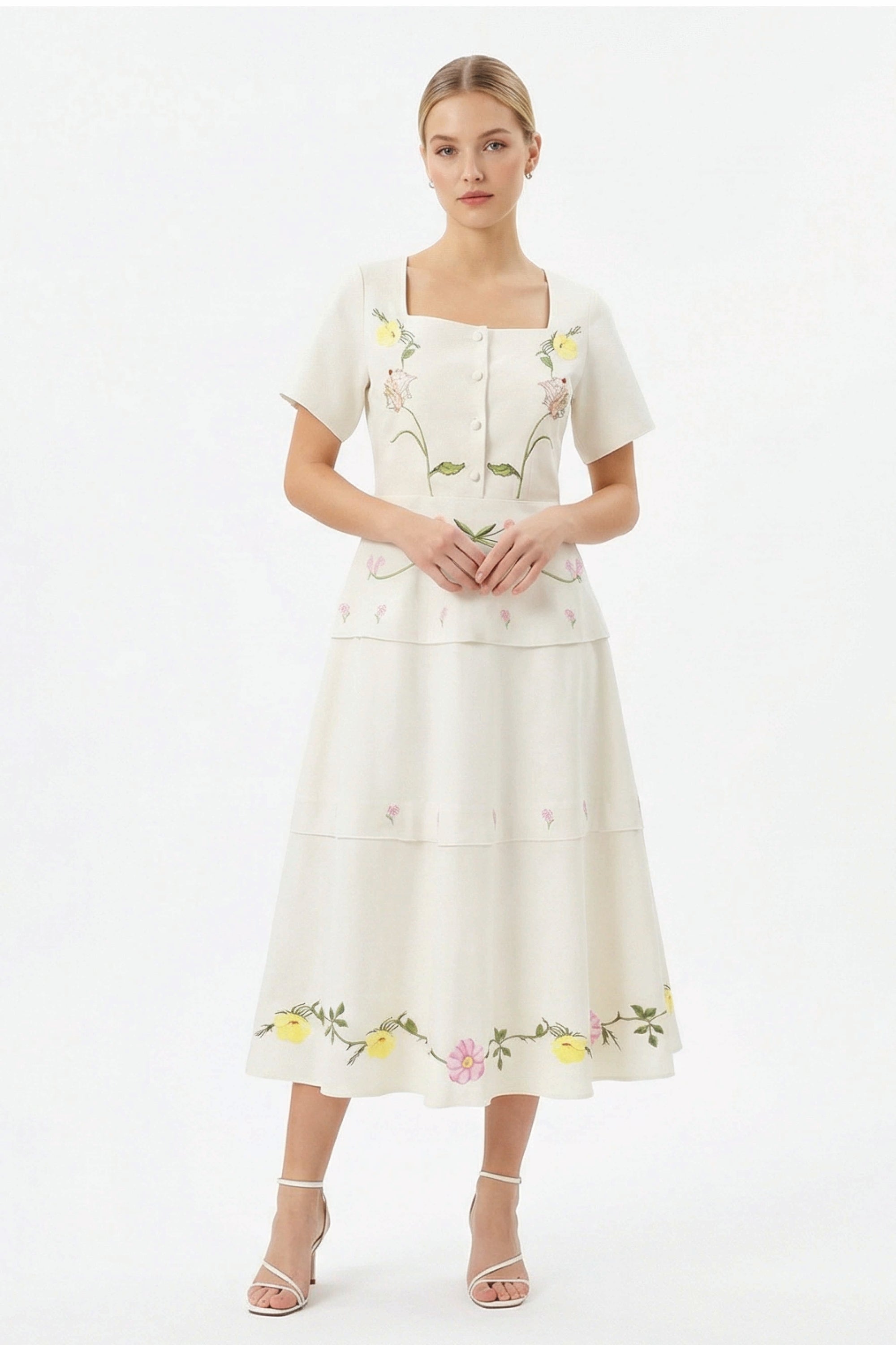 Model wearing the Fanm Mon Selma Dress featuring a square neckline, short sleeves, covered button-front detailing, embroidered bodice, peplum waist, and tiered midi silhouette.