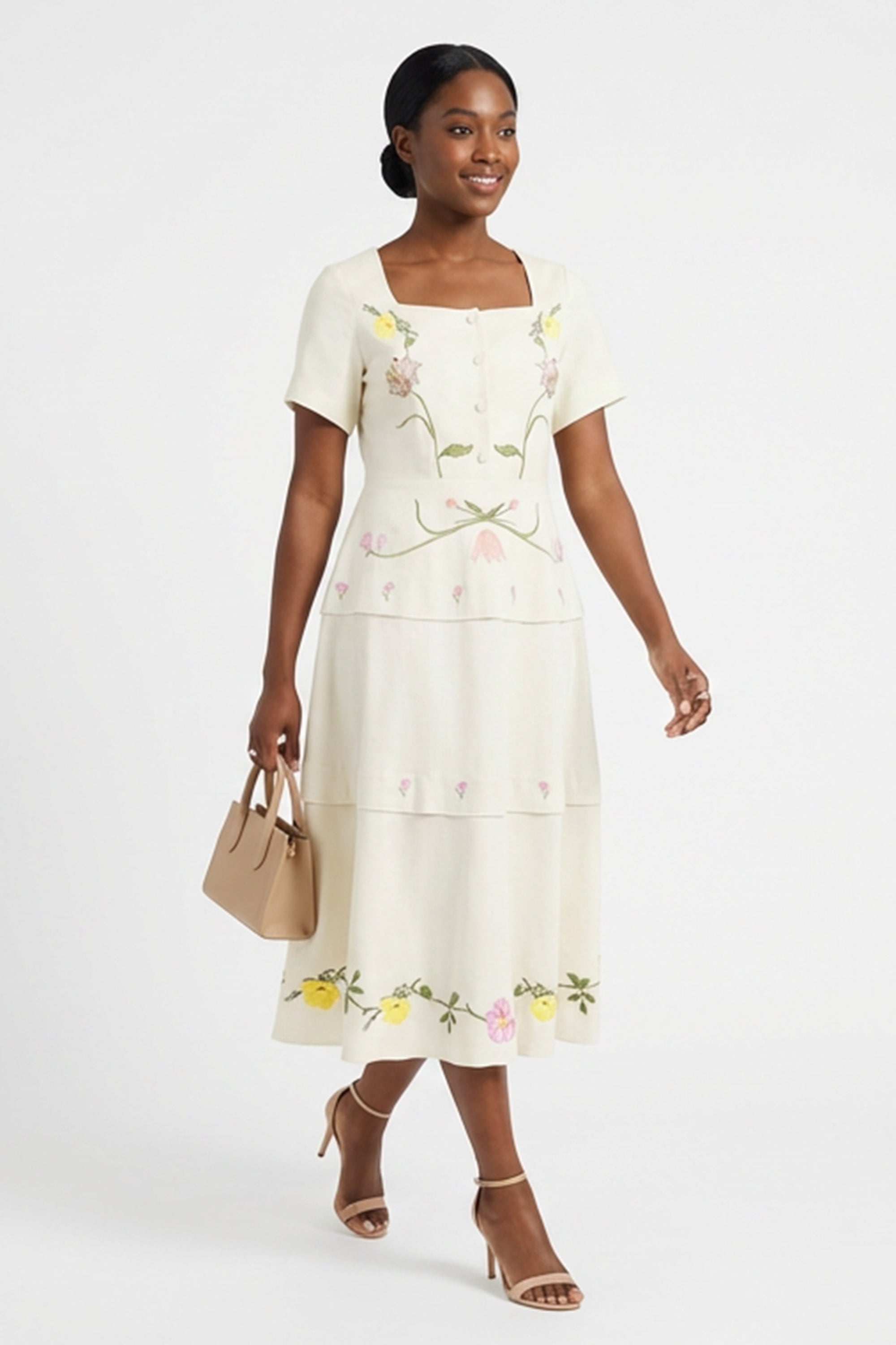 Model wearing the Fanm Mon Selma Dress showcasing the tailored square-neck bodice, peplum waist, embroidered floral detailing, and flowing tiered midi skirt.