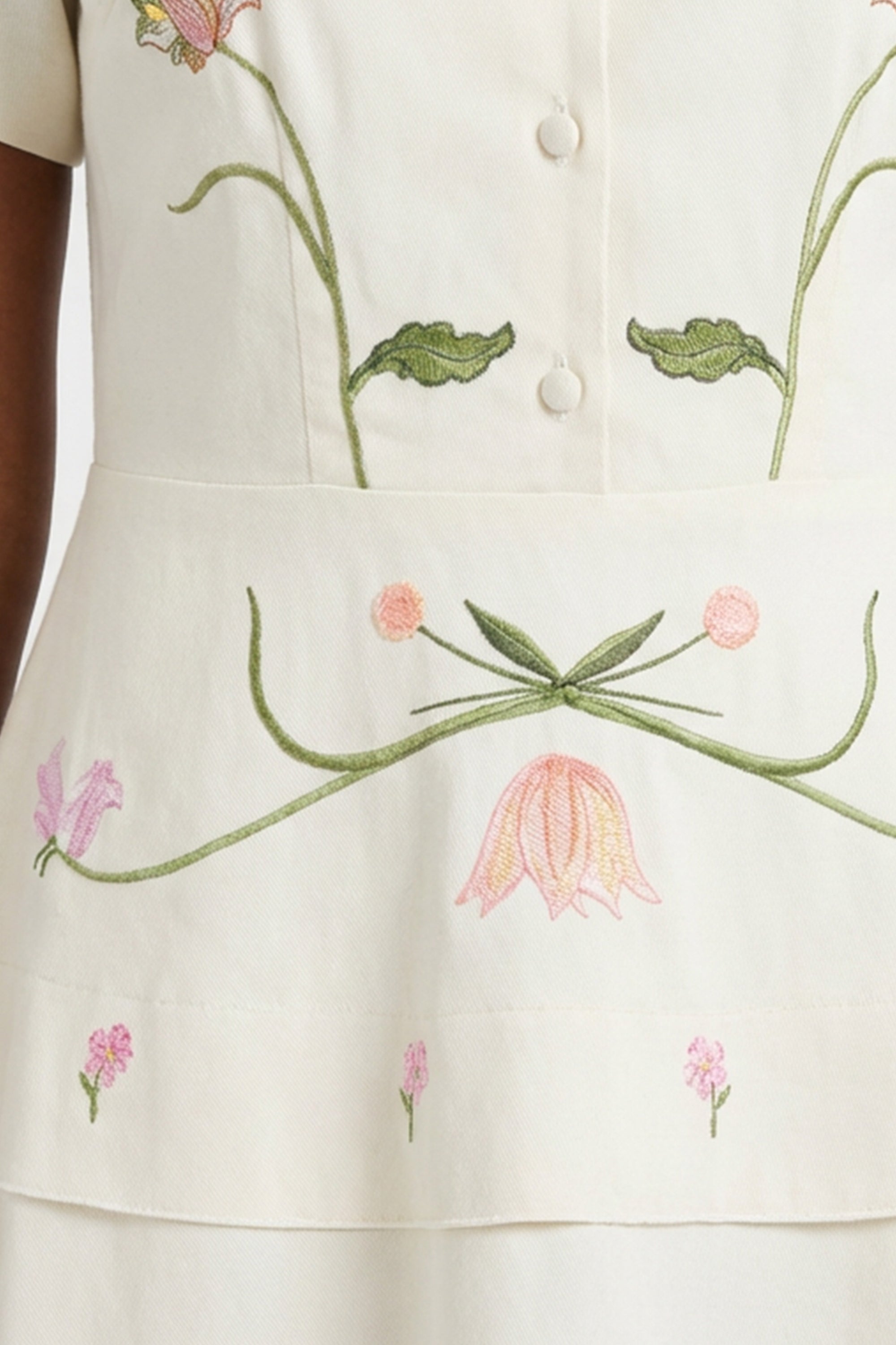 Close-up of the Fanm Mon Selma Dress highlighting the embroidered botanical motifs, decorative covered buttons, and intricate floral embroidery across the peplum waist.