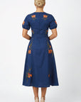 Back view of the Fanm Mon Simone Dress featuring floral embroidery, short puff sleeves, self-tie waist, and concealed back zip closure.