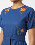 Close-up of the Fanm Mon Simone Dress highlighting intricate floral embroidery, round neckline, and self-tie waist.