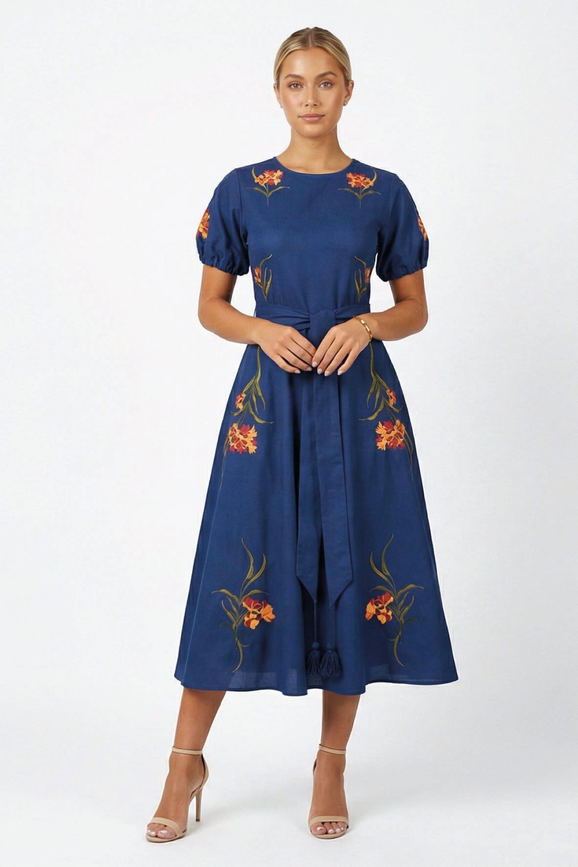 Model wearing the Fanm Mon Simone Dress featuring floral embroidery, short puff sleeves, a self-tie waist belt, and full midi skirt.