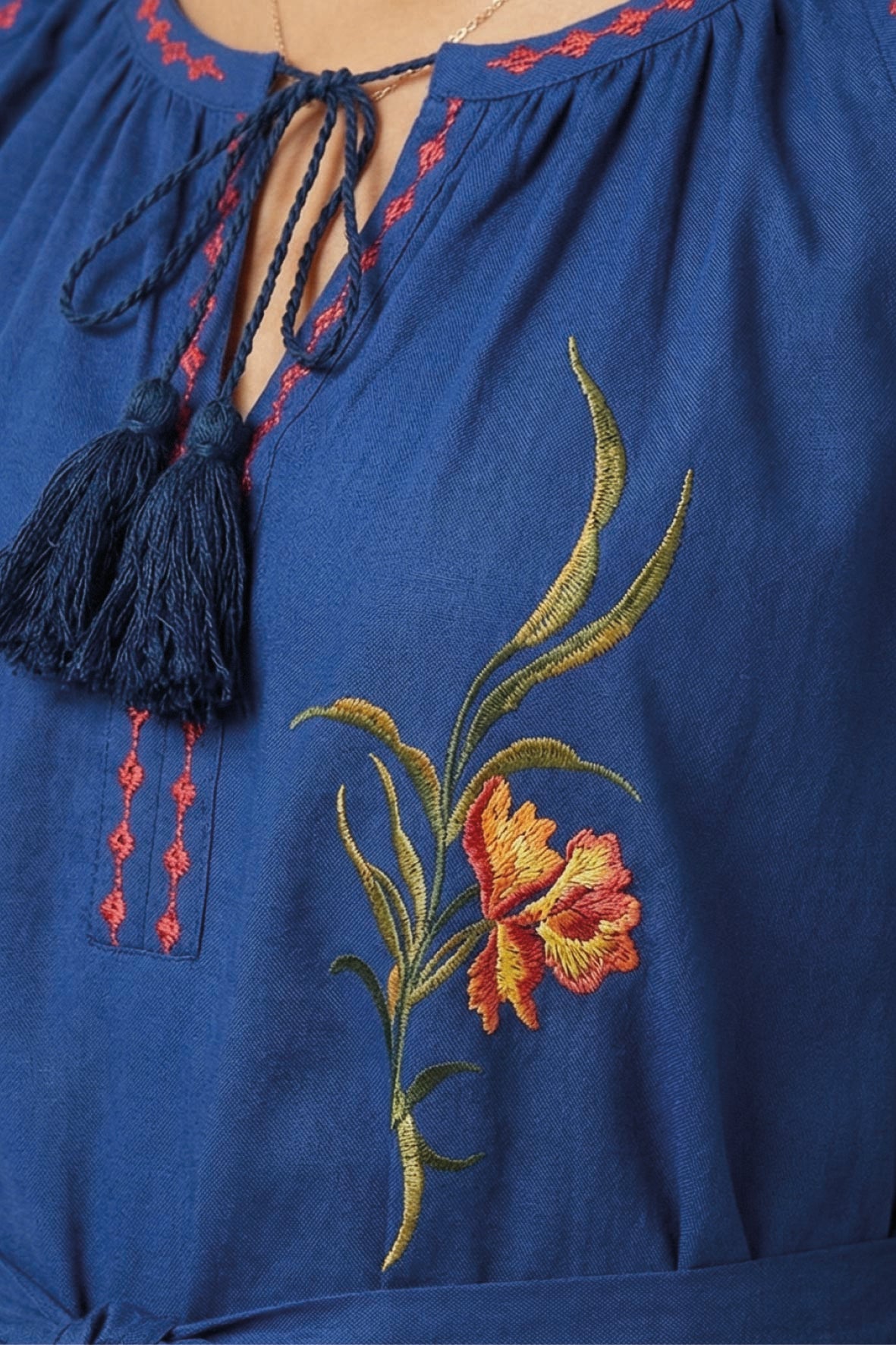 Close-up of the Fanm Mon Venya Dress highlighting the tassel tie neckline, contrast stitching, and intricate floral embroidery.