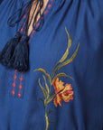 Close-up of the Fanm Mon Venya Dress highlighting the tassel tie neckline, contrast stitching, and intricate floral embroidery.