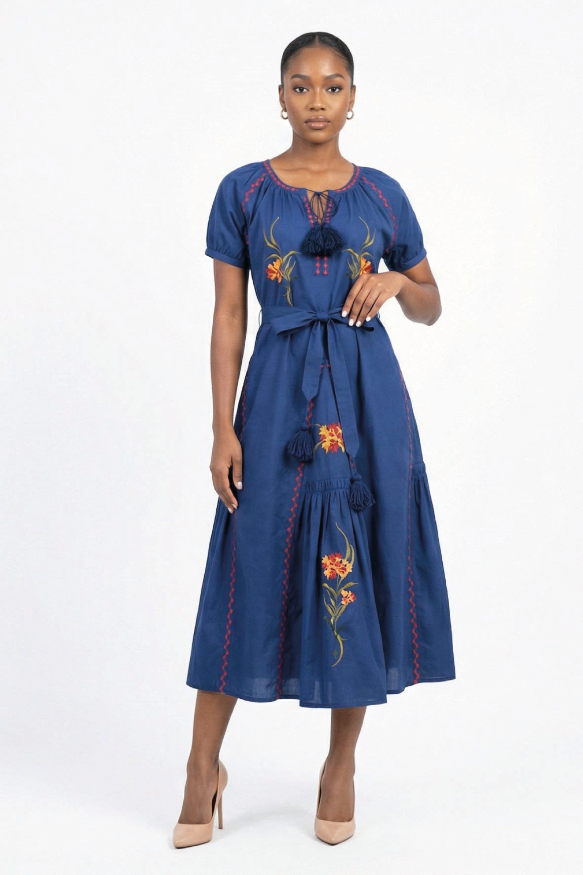 Model wearing the Fanm Mon Venya Dress featuring floral embroidery, short sleeves, tassel neckline, self-tie waist, and gathered midi skirt.
