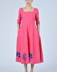 Fuchsia pink dress with blue coral-inspired embroidery on the hemline and square neckline. 