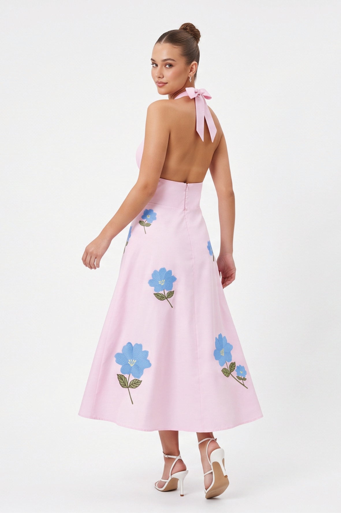 Back view of model wearing the Fanm Mon Ayna Dress with a halter tie, open back and blue floral embroidery.