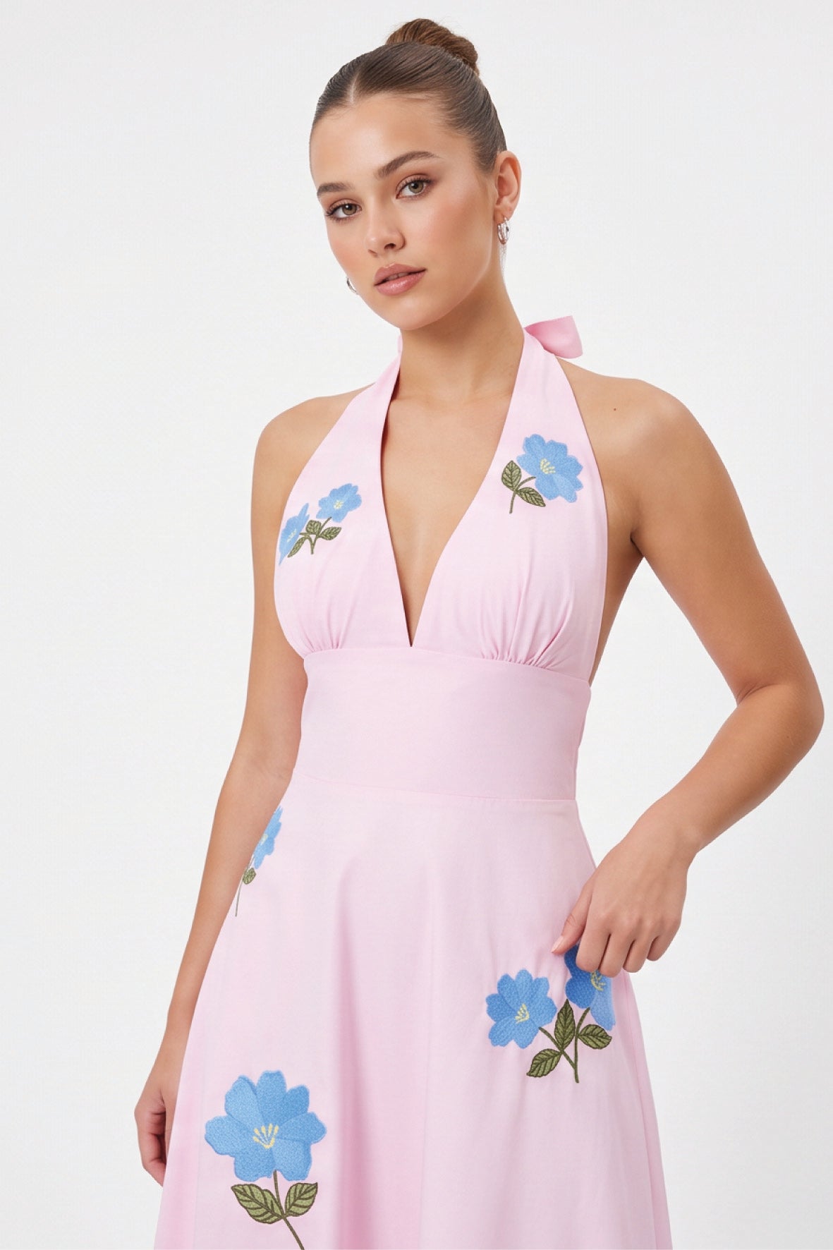 Detail of model wearing the Fanm Mon Ayna Dress with vivid blue floral embroidery accented by green leaves and yellow centers.