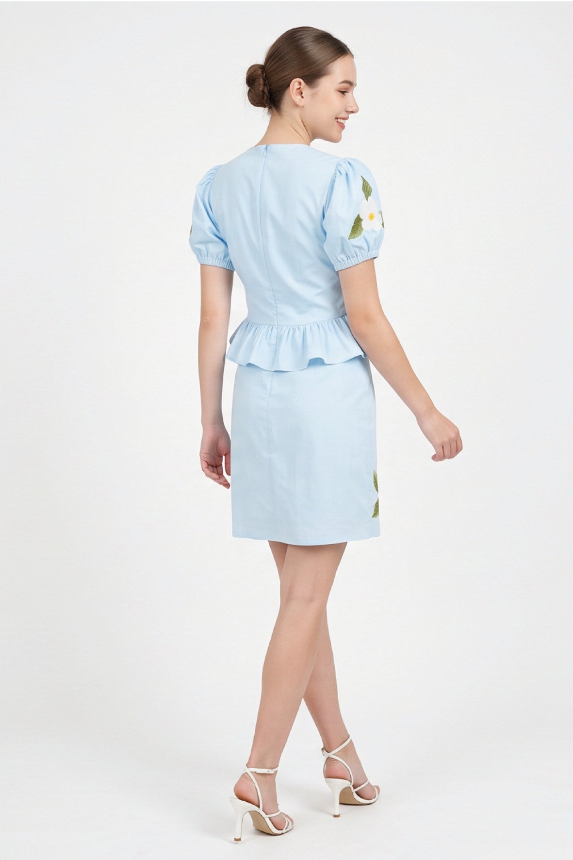 Back view of model wearing Fanm Mon Ether Set in light lagoon showing the fitted bodice, center-back zipper, gathered peplum hem, and tailored mini skirt