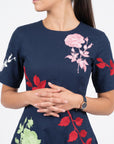 Close-up of Fanm Mon Gandi Dress in navy highlighting pink rose embroidery, contrasting red botanical motifs, and tailored short sleeves
